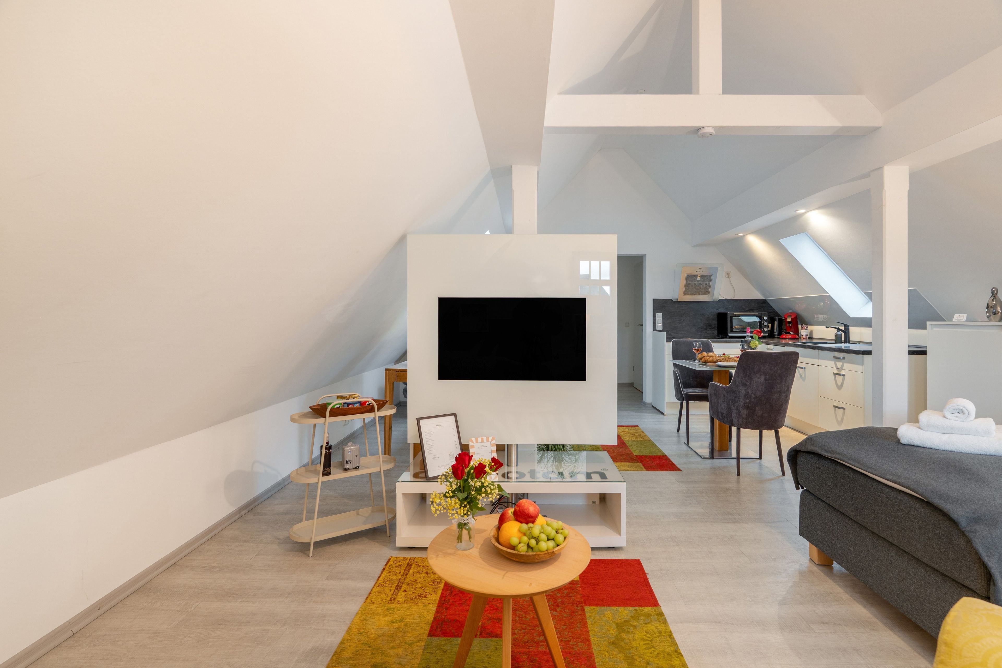 Un espace de vie moderne et compact, doté d’un téléviseur à écran plat, d’un coin repas et d’une kitchenette.