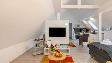 Un espace de vie moderne et compact, doté d’un téléviseur à écran plat, d’un coin repas et d’une kitchenette.