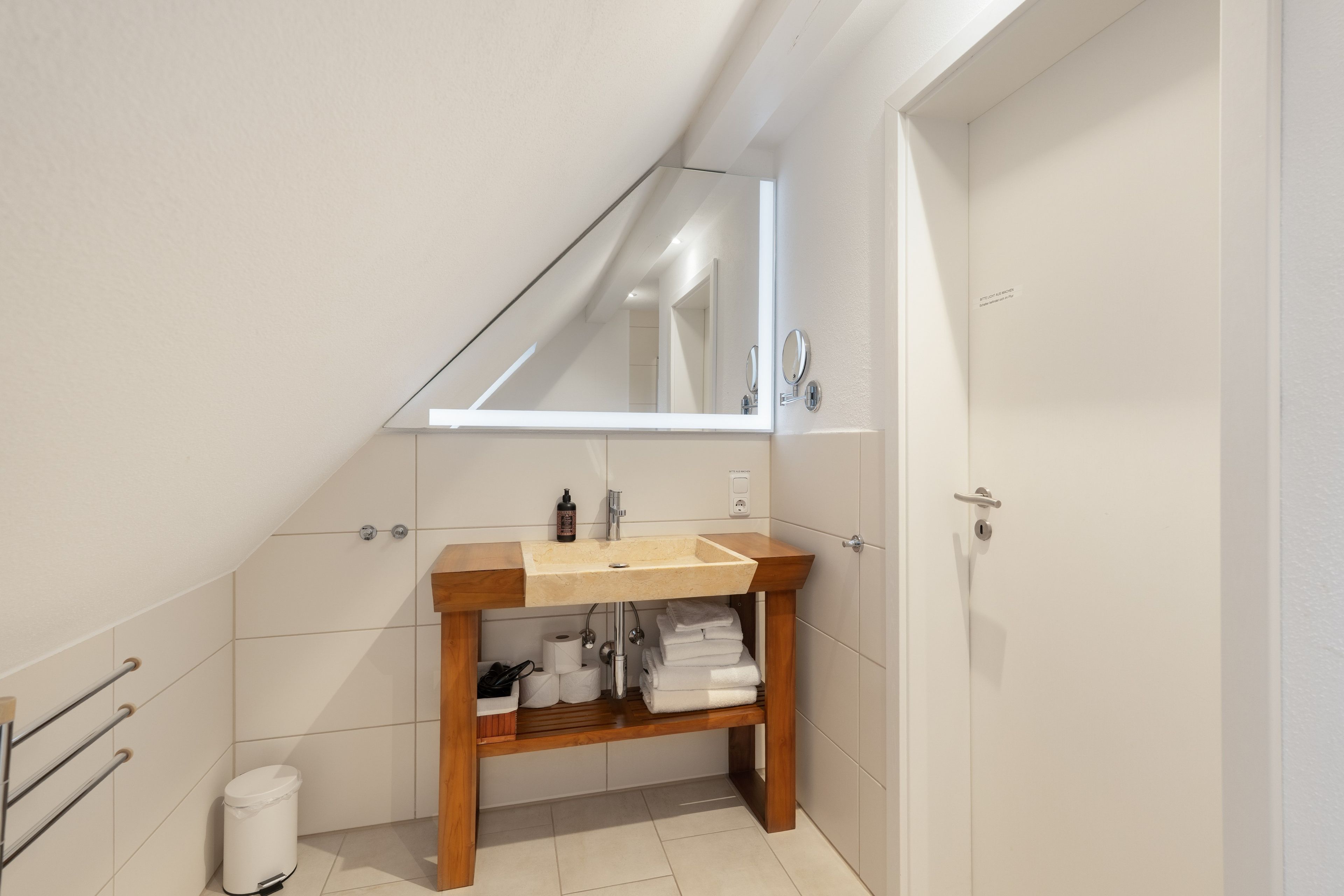 A bathroom with a wooden vanity, a mirror, a sink, and a toilet.