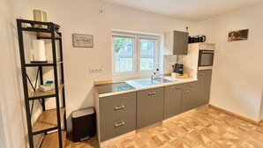 A compact kitchen with a window, a sink, a stove, and a shelf unit. - Vetera Apartment with Mountain View, Private Terrace & Wi-Fi (Bendorf)