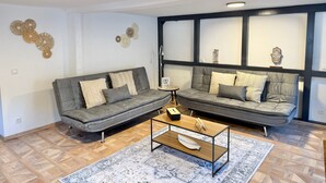 A modern living room with two grey sofas, a coffee table, and decorative wall art. - Vetera Apartment with Mountain View, Private Terrace & Wi-Fi (Bendorf)