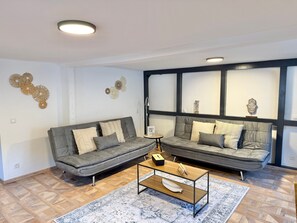 A modern living room with two grey sofas, a coffee table, and decorative wall art. - Vetera Apartment with Mountain View, Private Terrace & Wi-Fi (Bendorf)