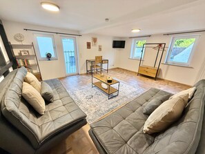 Ein Wohnzimmer mit zwei grauen Sofas, einem Couchtisch und einem an der Wand befestigten Fernseher.