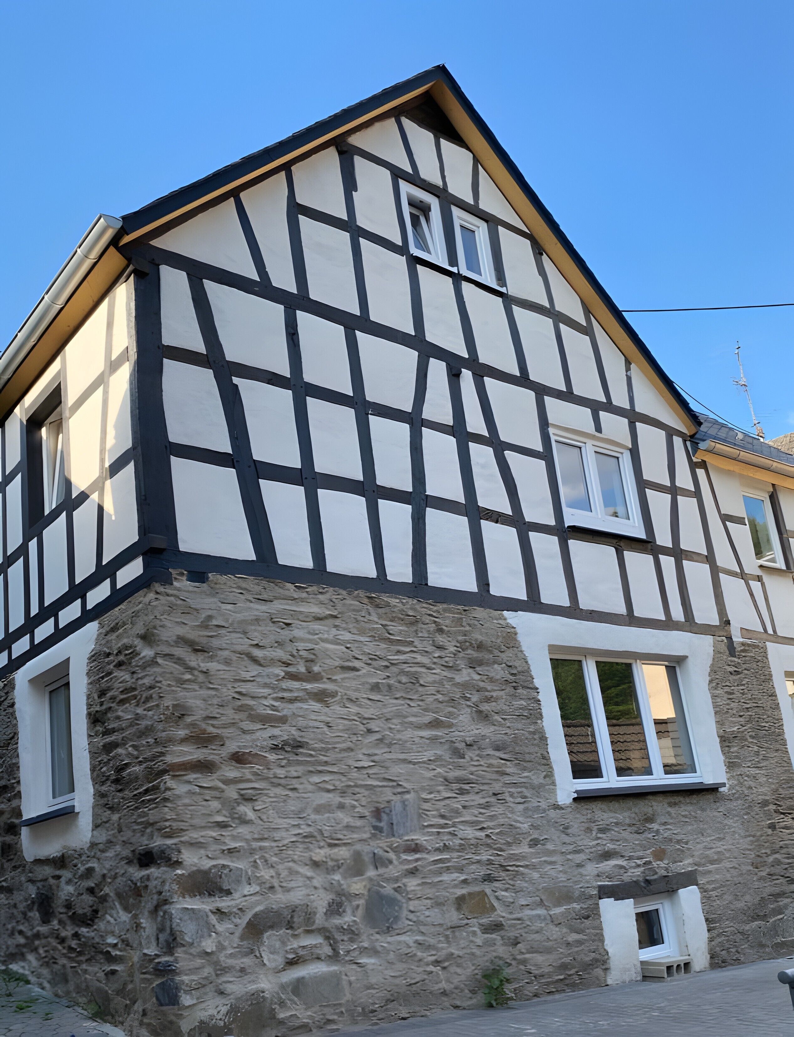 Un bâtiment à pans de bois, avec des murs en pierre et de nombreuses fenêtres.