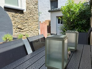 An outdoor seating area with a stone wall, a wooden fence, and a potted plant. - Vetera Apartment with Mountain View, Private Terrace & Wi-Fi (Bendorf)