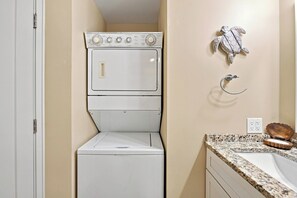 Granite counters and creamy walls frame a convenient laundry nook, tucked neatly beside the vanity for effortless chores. A playful sea turtle sculpture adds a whimsical touch to this clean, functional utility space. - Serene Villa Steps From Beach w/ Pool and Tennis! (Hilton Head Island)
