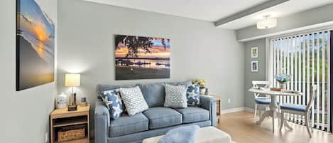 A living room with a sofa, a coffee table, a lamp, and artwork on the wall.