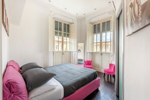 A bedroom with a bed, two chairs, and a window with shutters. - Charming two-story apartment located a 15-minute walk from St. Peter's (Roma)