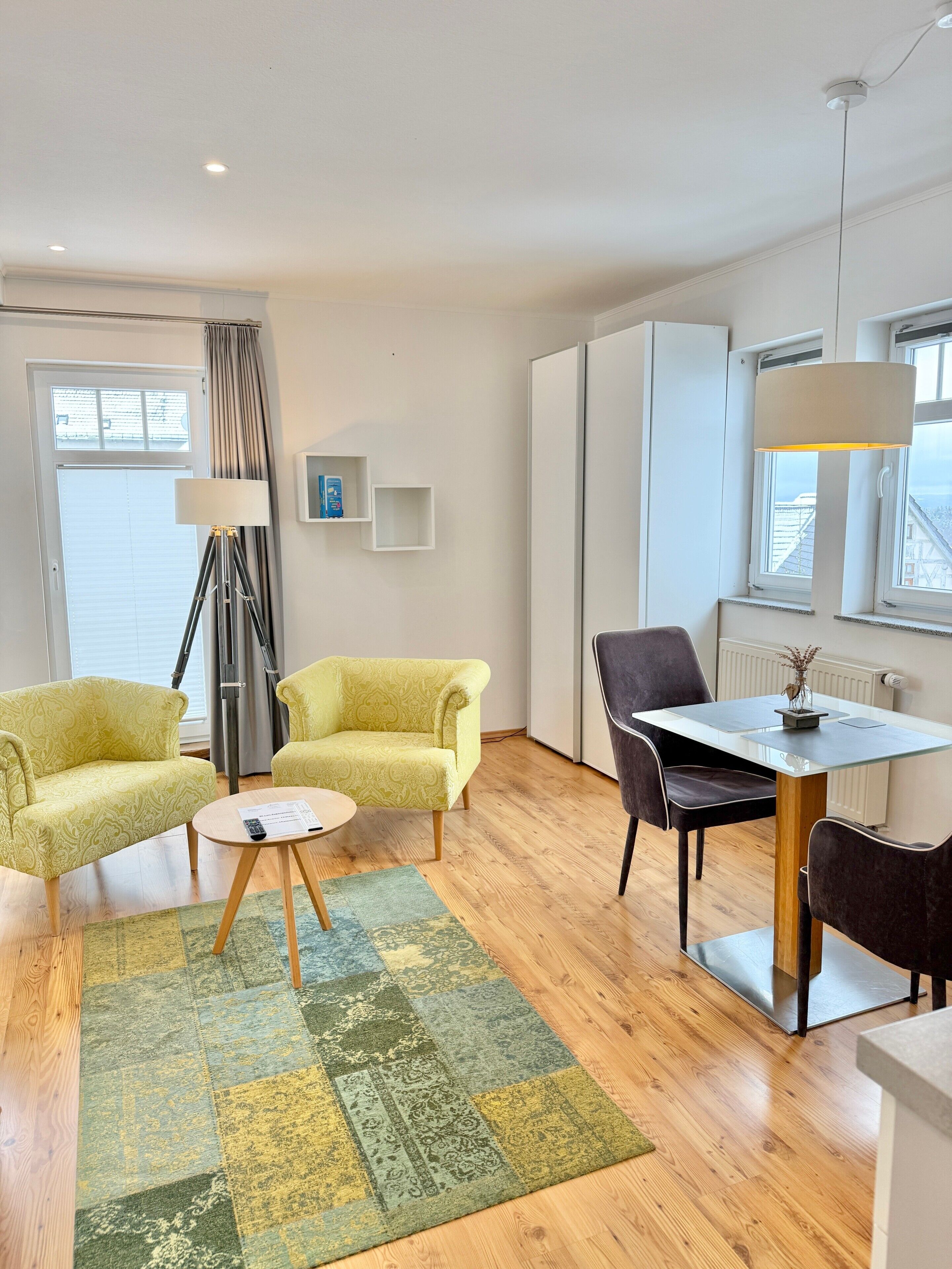 Een moderne woonkamer met een bank, fauteuil, salontafel en een eethoek met stoelen en een tafel.