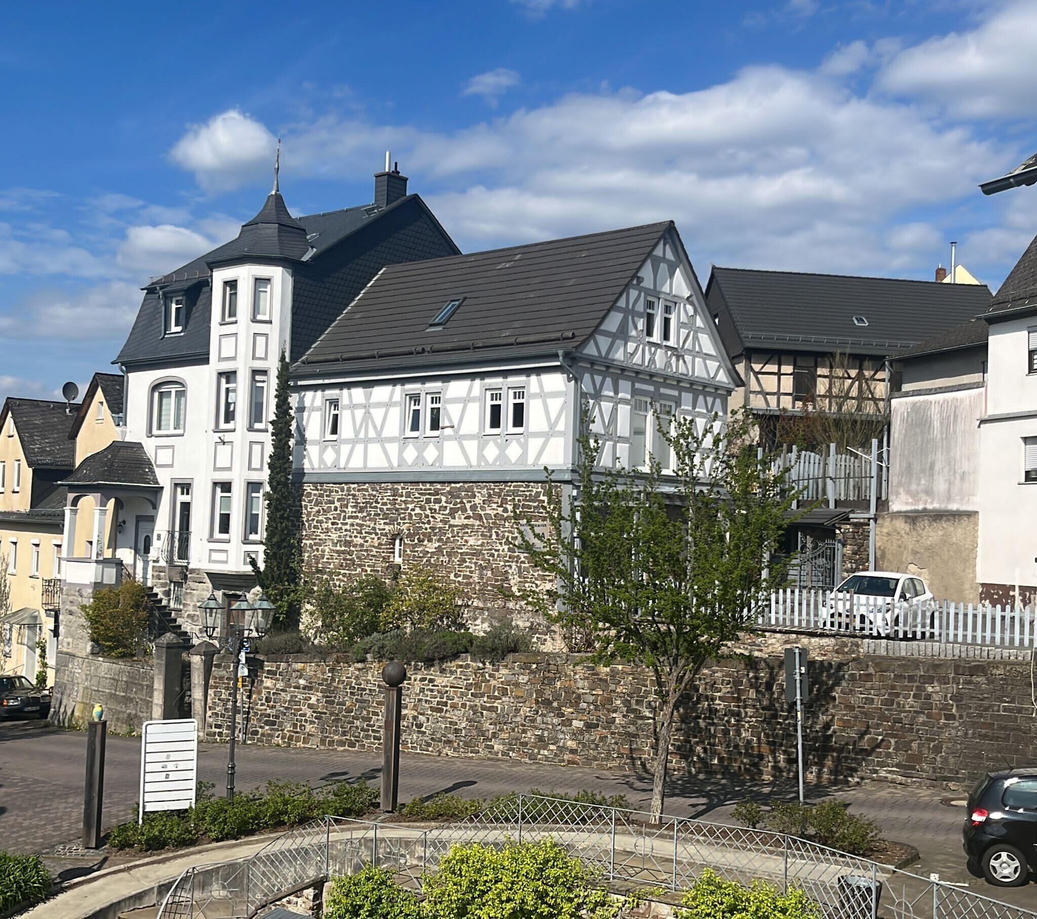 A traditional half-timbered building with a stone wall and a white facade.