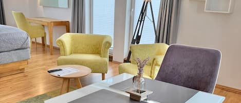Een hotelkamer met een bank, fauteuil, klein tafeltje en een lamp.