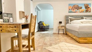 Ein modernes Schlafzimmer mit einem Holztisch, einem Bett mit grauem Kopfteil und einem Bild an der Wand.