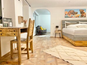 A modern bedroom with a wooden desk, a bed with a grey headboard, and a painting on the wall. - Apartment 'Ferienwohnung Kleinôd' with Private Terrace and Wi-Fi (Bendorf)