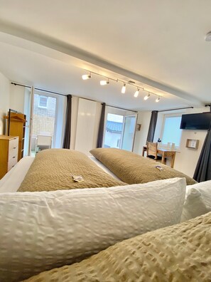 A hotel room with a bed, a desk, a chair, a TV, and a window. - Apartment 'Ferienwohnung Kleinôd' with Private Terrace and Wi-Fi (Bendorf)