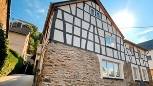 Ein traditionelles Fachwerkhäuschen mit Steinmauern und einer gepflasterten Auffahrt.