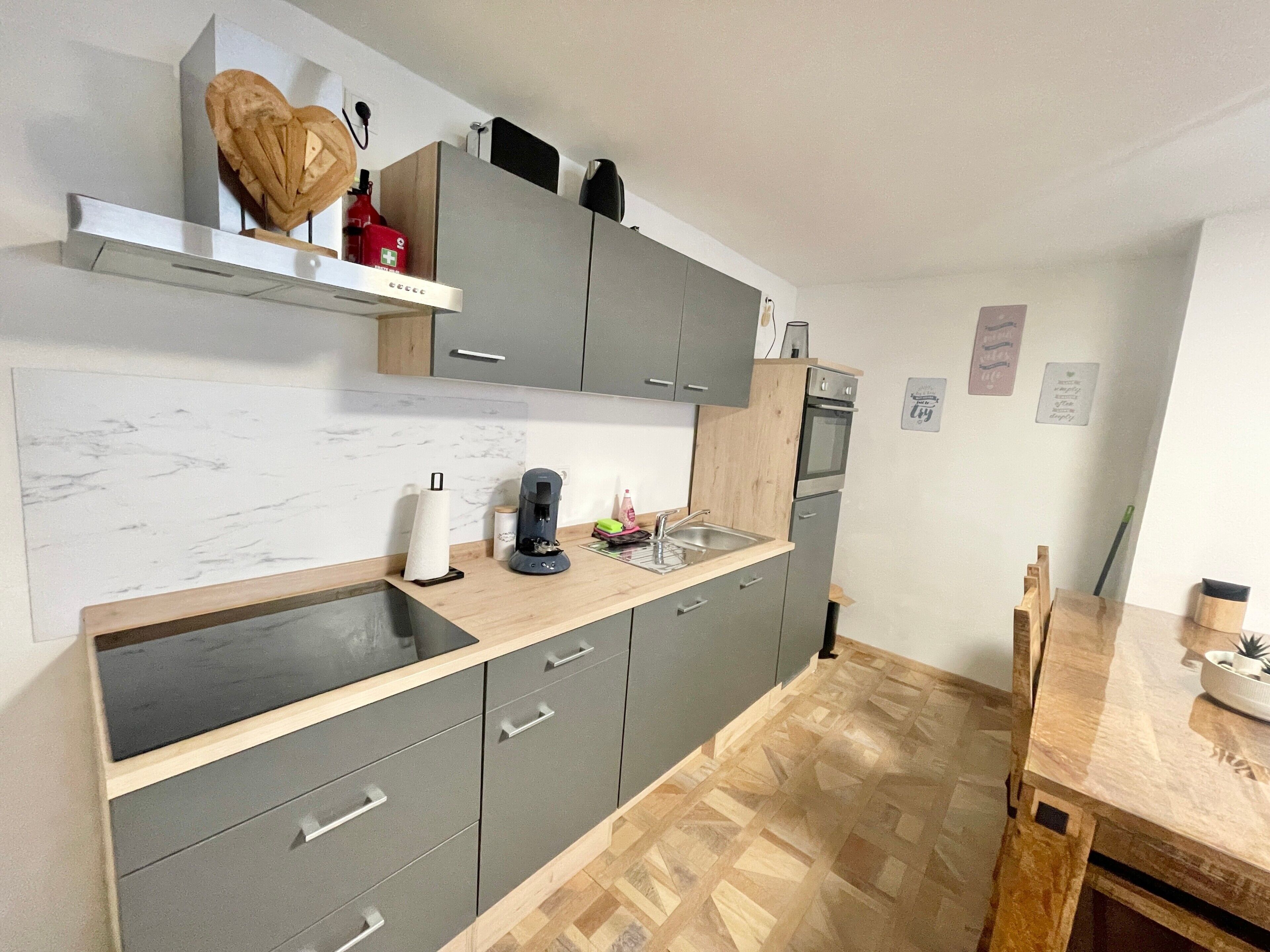A modern kitchen with grey cabinets, a wooden countertop, and a built-in oven.