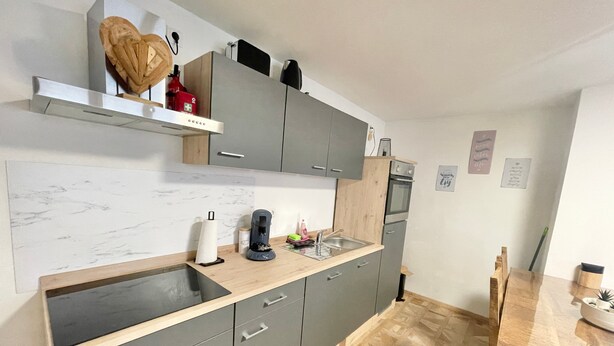 Eine moderne Küche mit grauen Schränken, einer Holzauskładung und einem eingebauten Ofen.