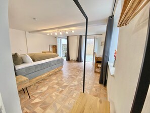 Ein modernes Schlafzimmer mit Schlafsofa, Holzboden und Blick ins Freie.