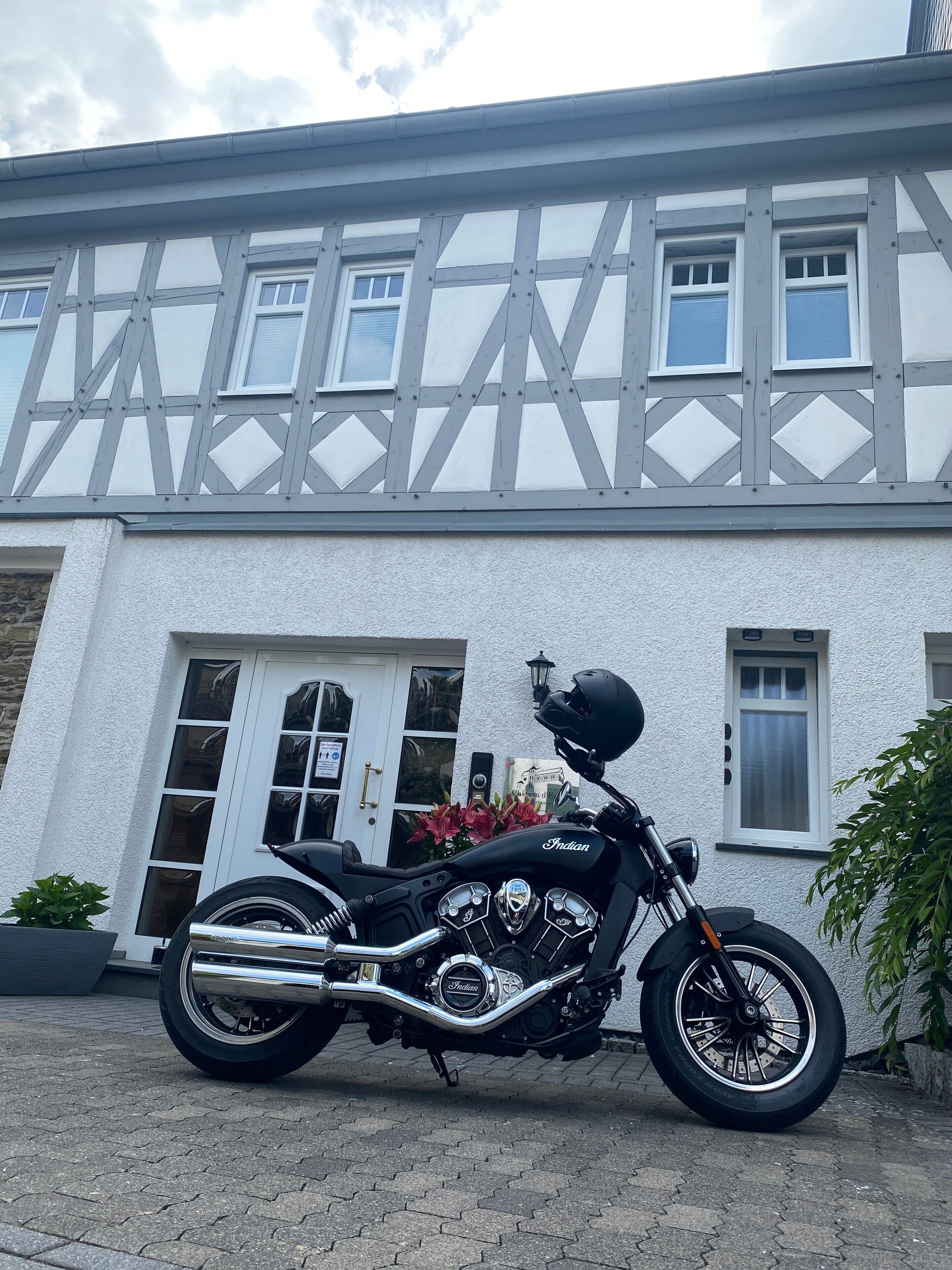 Ein Motorrad vor einem Gebäude mit weißer Fassade und Fachwerkkonstruktion.