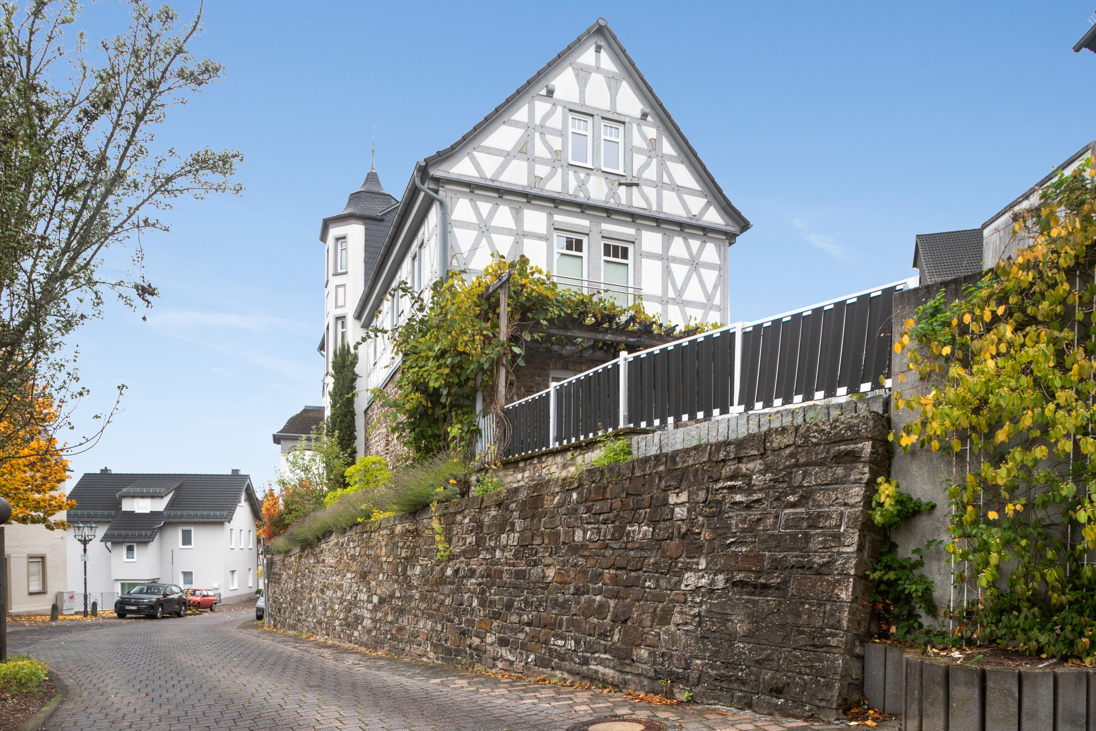 Une maison traditionnelle à colombages, avec un mur en pierre et une rue pavée.