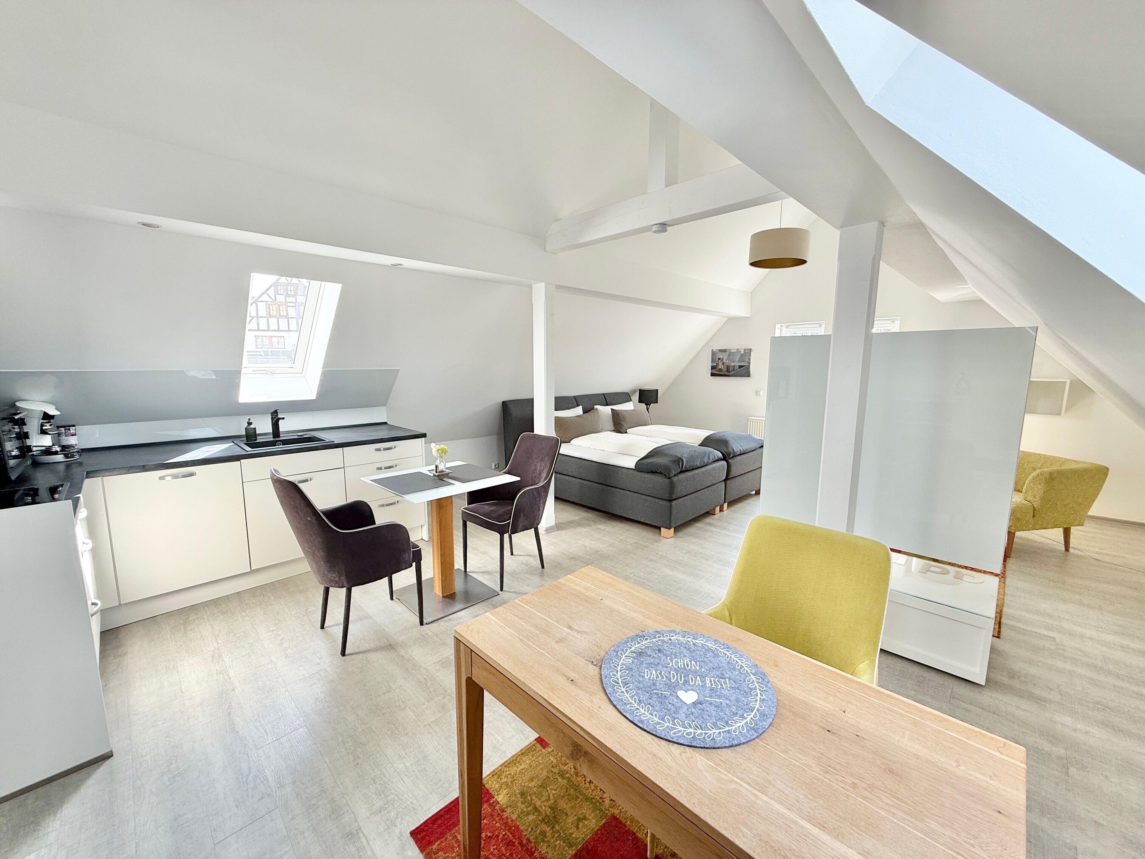 A modern loft apartment with a kitchen, dining area, and sleeping space.