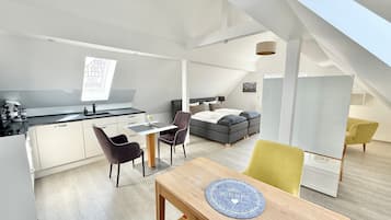 A modern loft apartment with a kitchen, dining area, and sleeping space.