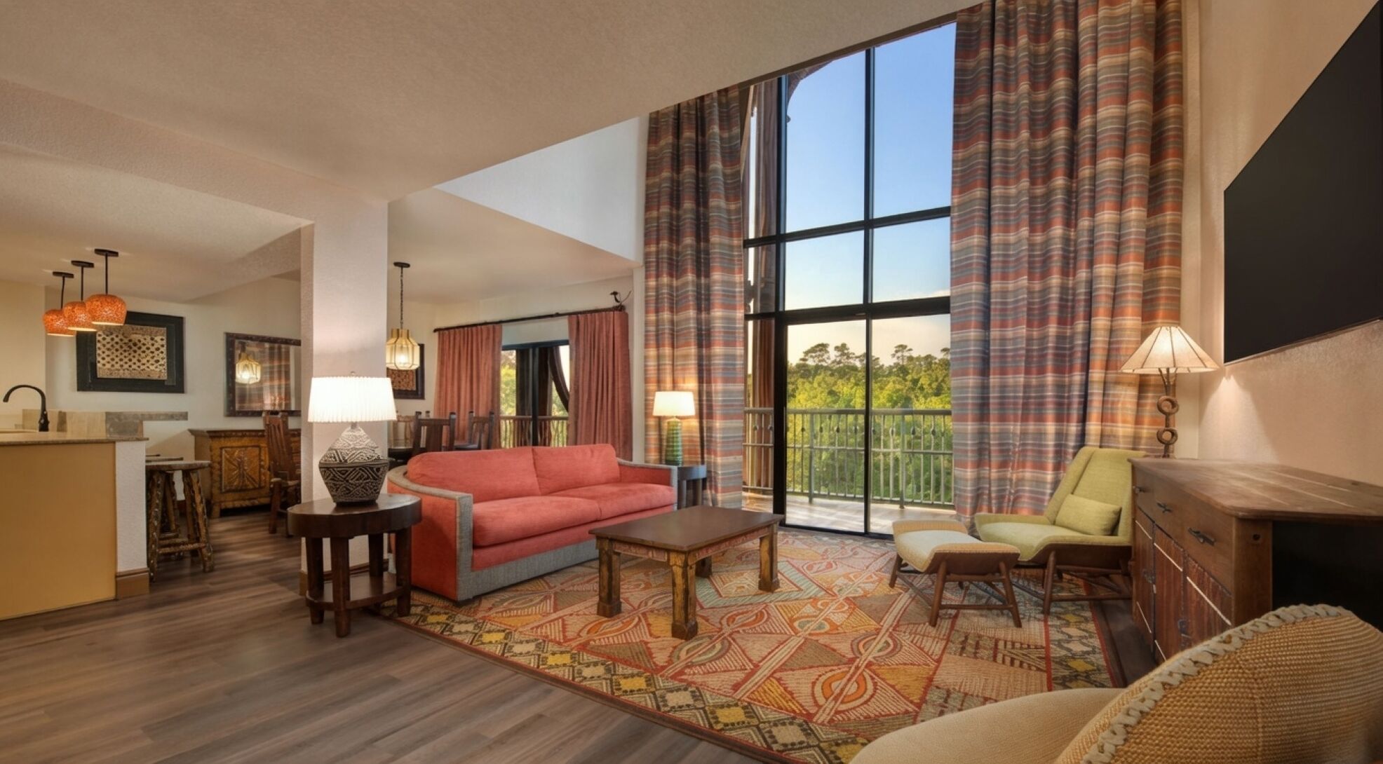 A spacious living area with a large window, a sofa, a coffee table, and a dining area with a table and chairs.