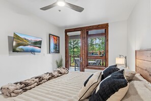 A bedroom with a bed, a large window, a ceiling fan, and artwork on the wall. - Luxury Mountain Escape | Steps to Snowflake Lift with Resort Amenities (Breckenridge)