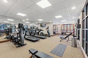 Ein Fitnessraum mit Laufbändern, Crosstrainern und Trainingsmatten.