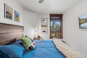 Ein Schlafzimmer mit einem Bett, einem Nachttisch, einer Lampe und gerahmten Bildern an der Wand.