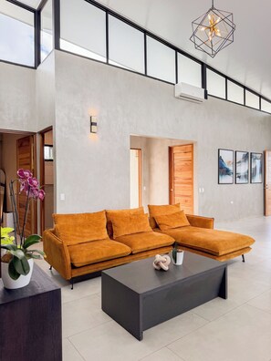 A spacious living area with a sectional sofa, a coffee table, and a modern pendant light. - Cloud Forest Villa (Valle Azul)