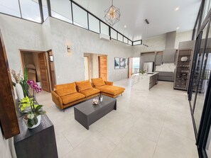 Ein geräumiger Wohnbereich mit einer Couch, einem Couchtisch und einer Küche im Hintergrund.