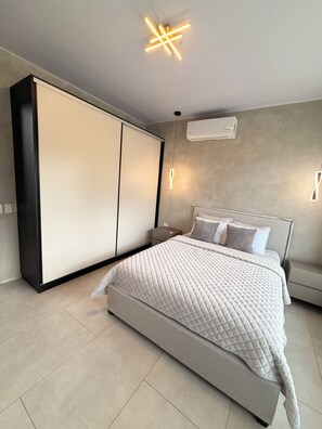 A modern bedroom with a large bed, a wardrobe, and a ceiling light fixture. - Cloud Forest Villa (Valle Azul)