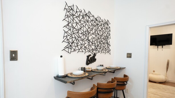 Eine moderne Küche mit geometrischer Wandkunst, einer Bar mit Hockern und einem an der Wand befestigten Fernseher.
