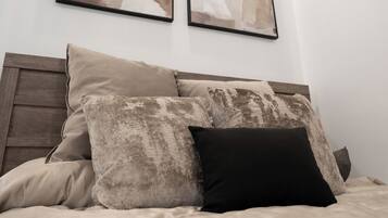 Un dormitorio con una cama, almohadas y dos cuadros abstractos en la pared.