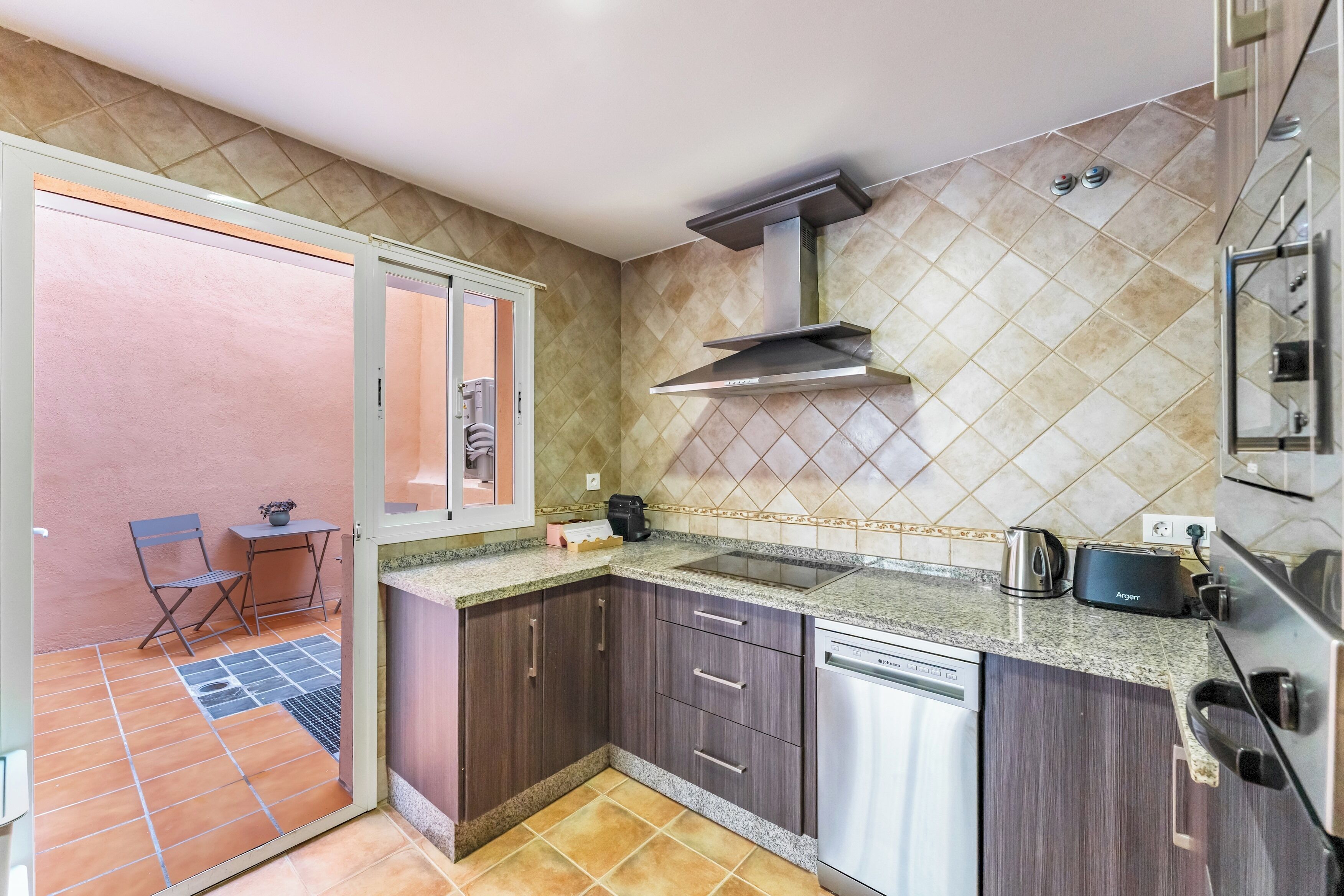 A compact kitchen with a built-in dishwasher, a gas stove, and a stainless steel range hood.