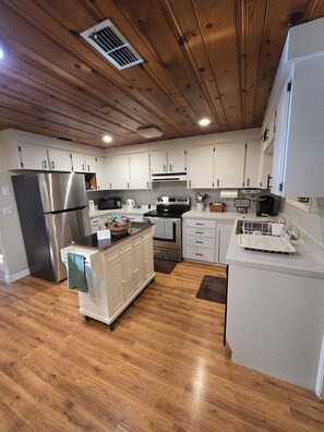 A modern kitchen with wooden ceiling beams, stainless steel appliances, and white cabinetry. - 3-bedroom Chassahowitzka River, by campground, pet friendly
Manatee retreat (Homosassa)