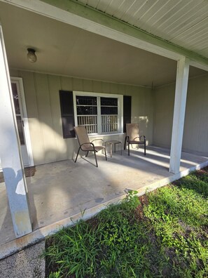 A covered porch with a table and chairs, a window with shutters, and a door. - 3-bedroom Chassahowitzka River, by campground, pet friendly
Manatee retreat (Homosassa)