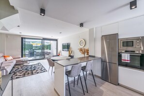 A modern kitchen with a central island, stainless steel appliances, and a dining area with a sofa and chairs. - 3 Bed Townhouse Escape Costa Del Sol - Pass the Keys (Fuengirola)