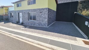 Een twee verdiepingen tellend huis met een gele gevel, stenen details en een geplaveid oprit.