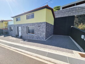 Ein zweistöckiges Haus mit gelber Fassade, Steinzierarbeiten und einem gepflasterten Einfahrt.