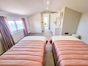 Ein Hotelzimmer mit zwei Betten, einem Kleiderschrank, einem Schminktisch und Blick auf das Treppenhaus.