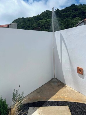 Eine Gebäudeecke mit weißer Wand, einem Metallpfosten und einer kleinen Fläche Erde.