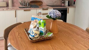 Moderni keittiö, jossa on pyöreä ruokapöytä, riippuvalaisin ja maljakko, jossa on kukkia.