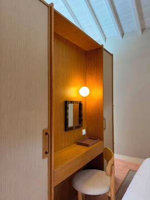 Ein Zimmer mit Holzschrank, Schreibtisch mit Spiegel und Stuhl.