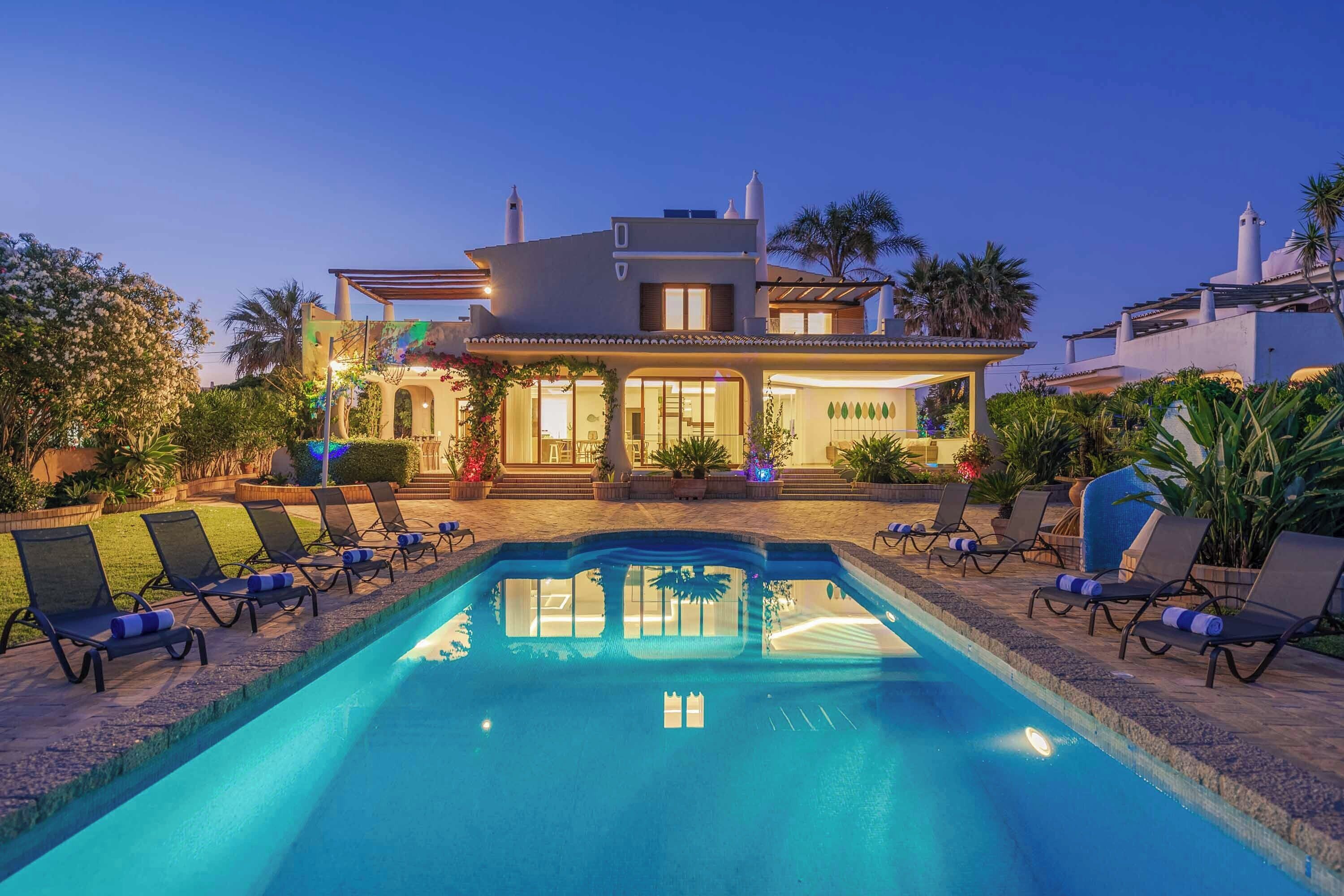 A two-story house with a swimming pool and lounge chairs.