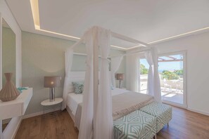 A bedroom with a canopy bed, a bedside table with a lamp, a small round table, and a view of the outdoors. - Casa da Praia - Four Bedroom Villa, Sleeps 8 (Algarve)