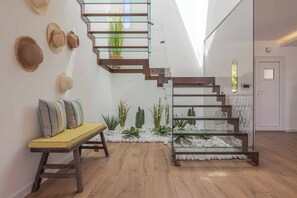 A modern interior with a wooden staircase, a bench with cushions, and a small indoor garden. - Casa da Praia - Four Bedroom Villa, Sleeps 8 (Algarve)