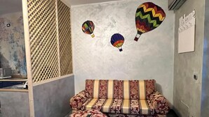 A room with a sofa and ottoman, a wooden partition, and a wall with a 'Welcome' sign.