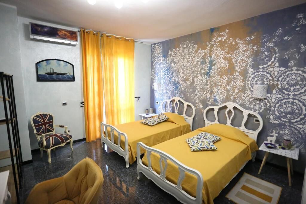 Une chambre d’hôtel avec deux lits simples, une chaise, une petite table et un mur décoratif.